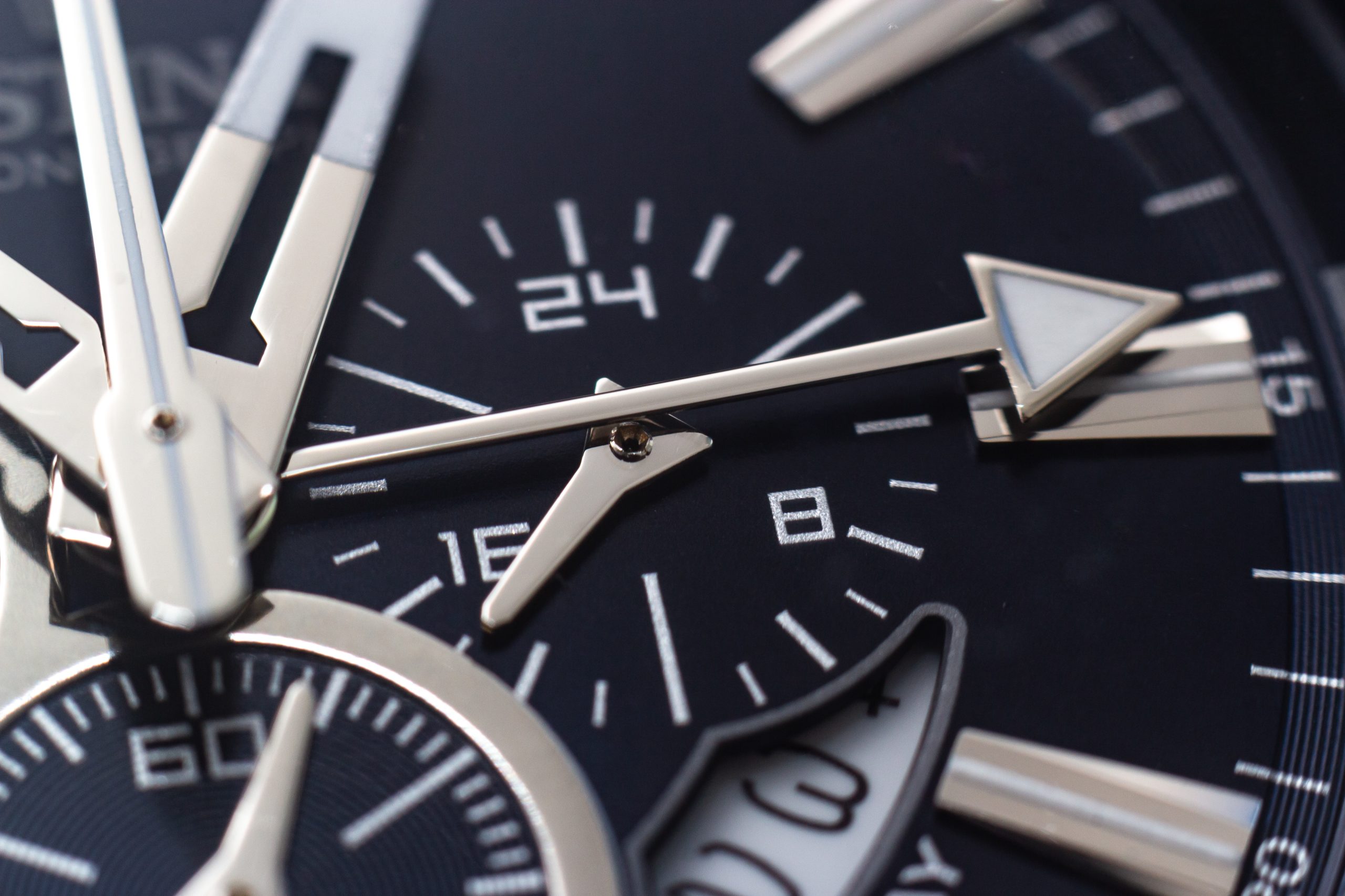 A closeup shot of the hands, numbers and hour marks of a black watch